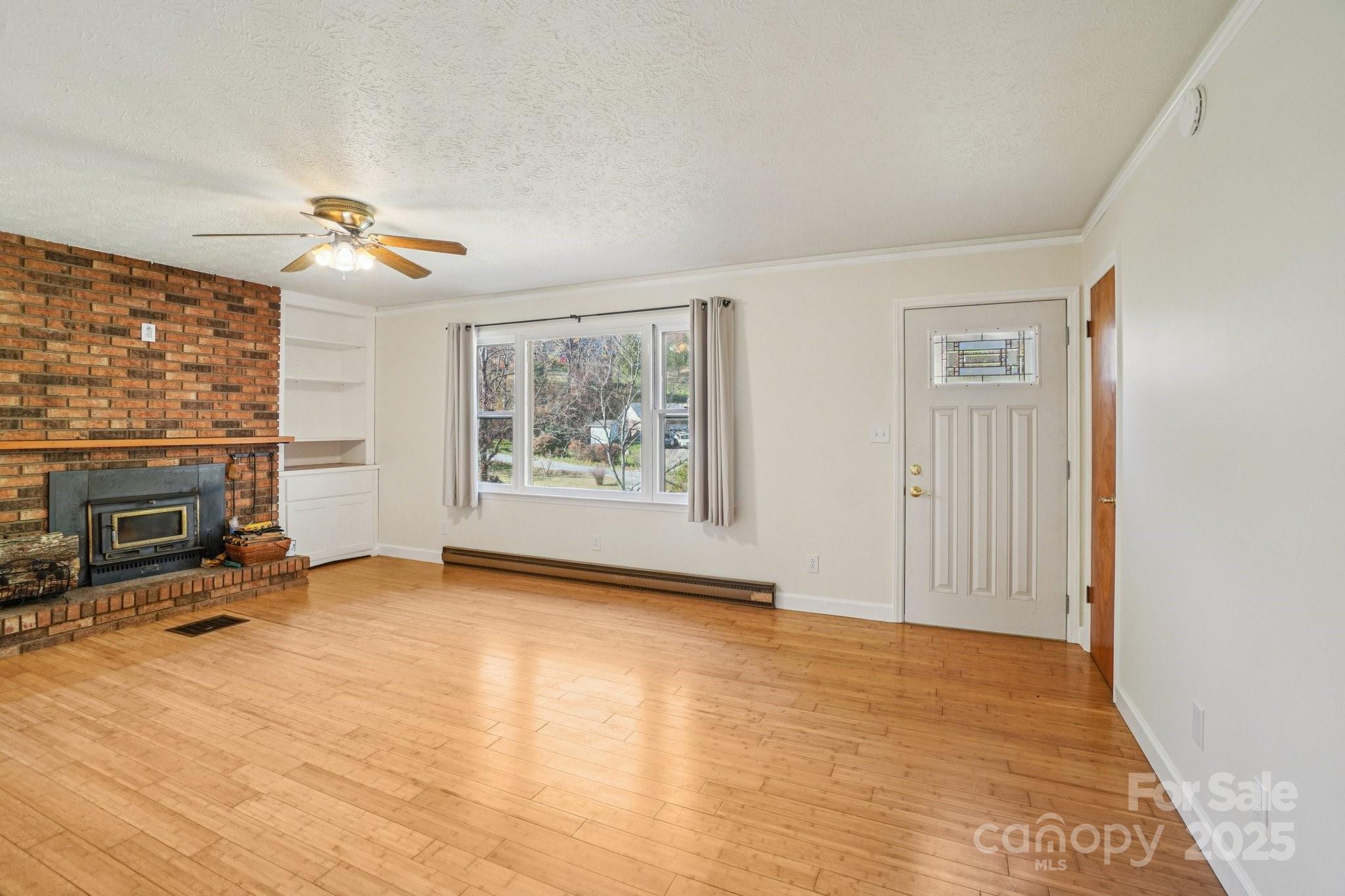 480 Paint Fork Road Barnardsville, NC 28709 - Photo 10 of 43 wooden floor fireplace and windows in an empty room