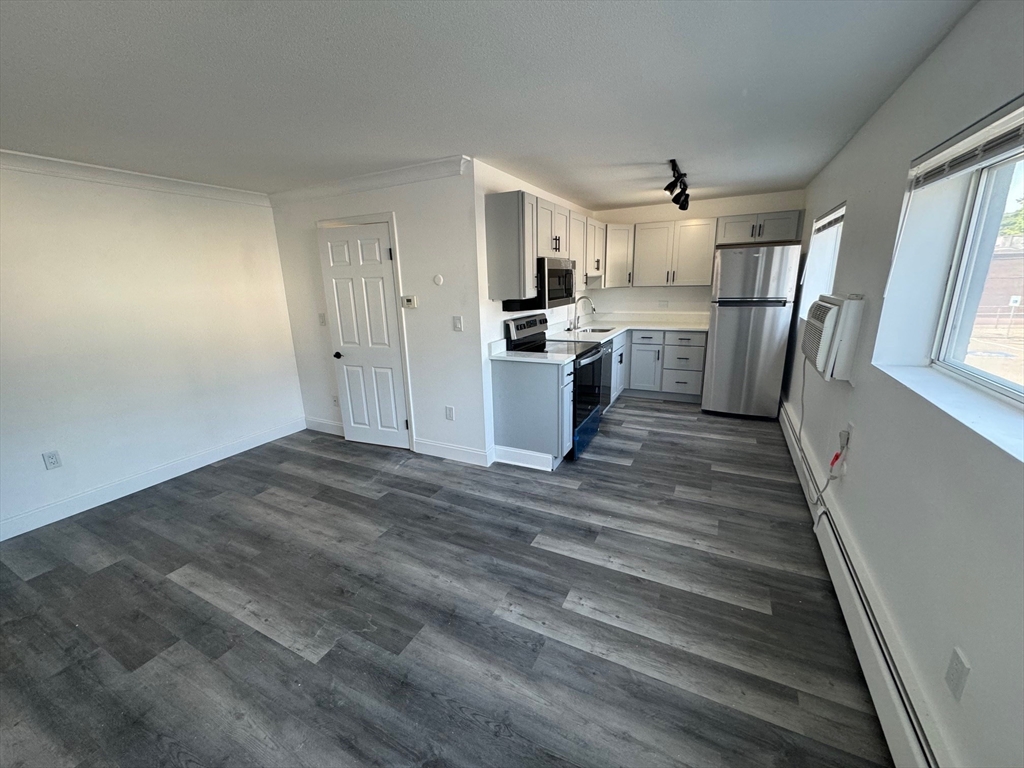 181 School Street, Unit 5 Waltham, MA 02451 - Photo 2 of 5 a view of a kitchen with wooden floor and electronic appliances