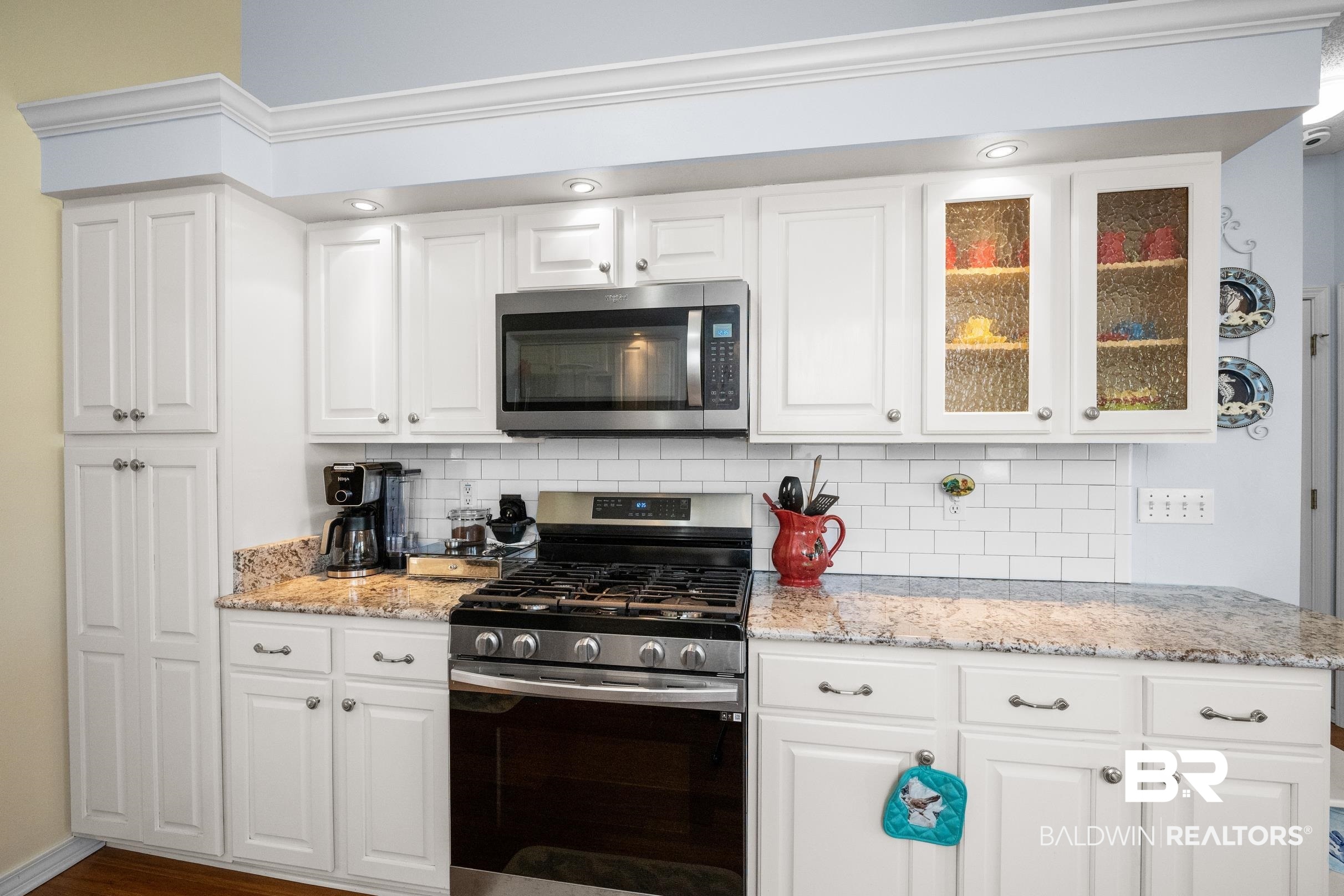 22355 East County Road 12 Foley, AL 36535 - Photo 17 of 54 Kitchen with appliances with stainless steel finishes, decorative backsplash, light stone countertops, glass insert cabinets, and white cabinetry