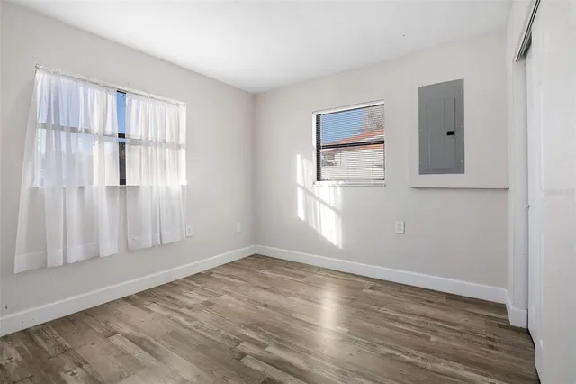 an empty room with wooden floor and windows