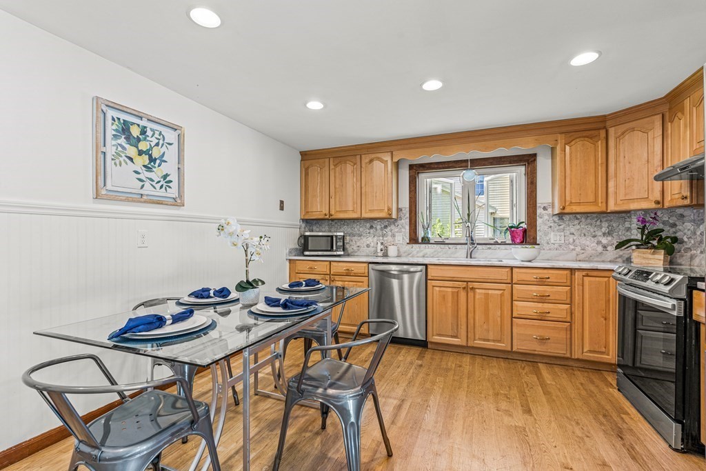 11 Main Street Winchester, MA 01890 - Photo 12 of 41 a kitchen with stainless steel appliances kitchen island granite countertop a stove a sink a dining table and chairs