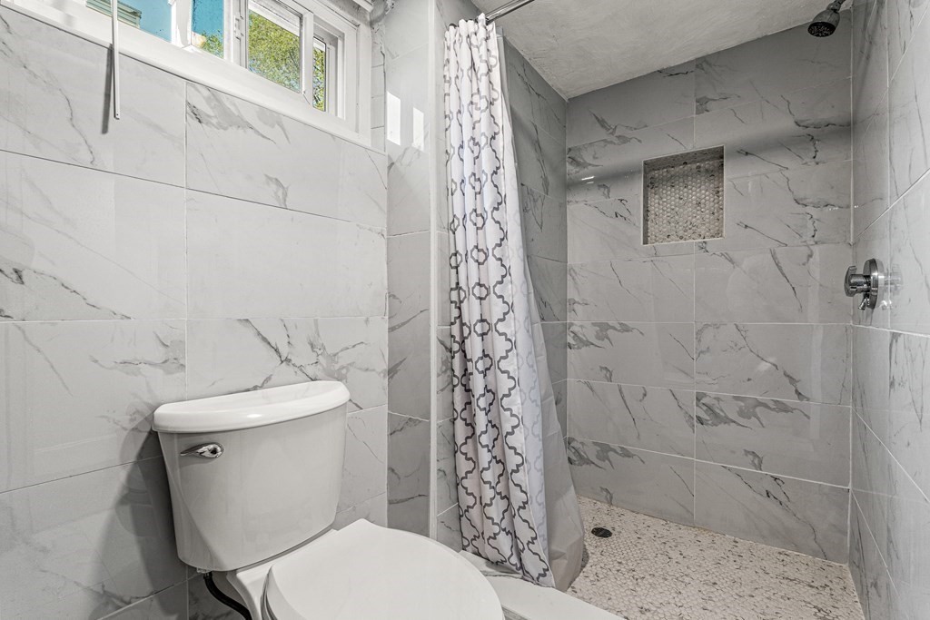 11 Main Street Winchester, MA 01890 - Photo 28 of 41 a white toilet sitting next to a shower curtain