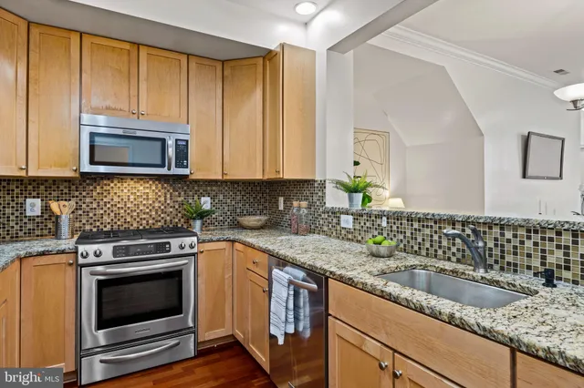 a kitchen with granite countertop a sink a stove and cabinets