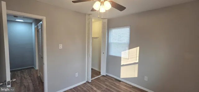 a view of a hallway with wooden floor and chandelier fan