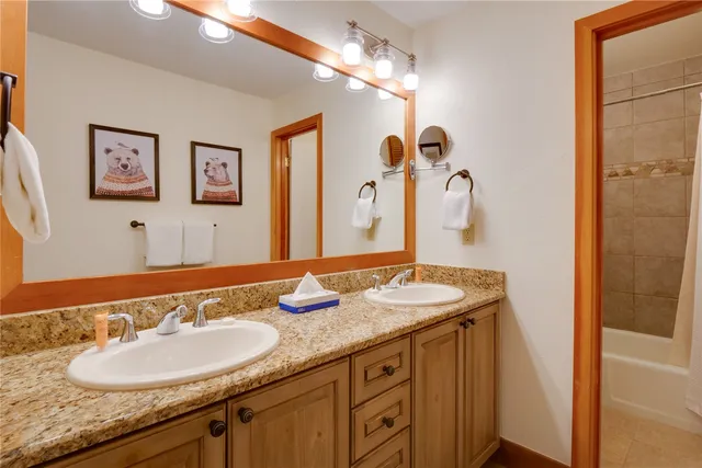 a bathroom with a granite countertop double vanity sink and a mirror
