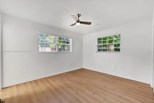 a view of empty room with wooden floor and fan