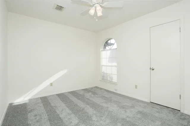 an empty room with windows and ceiling fan