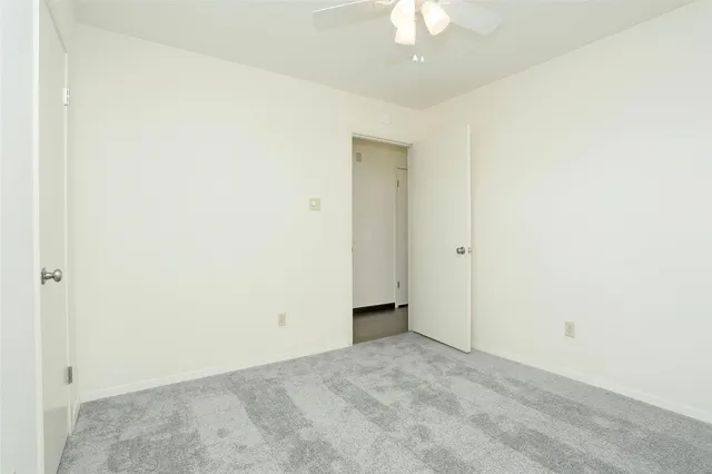 an empty room with a chandelier fan and closet area