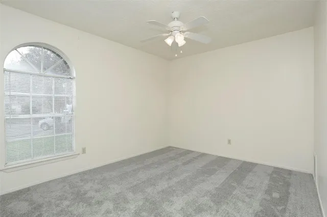 an empty room with a chandelier fan and windows