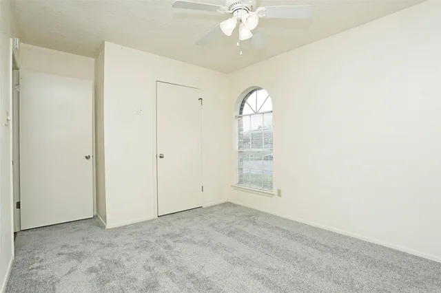 an empty room with a chandelier fan and windows