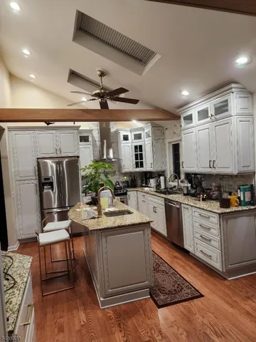 a kitchen with stainless steel appliances kitchen island granite countertop a sink stove and refrigerator