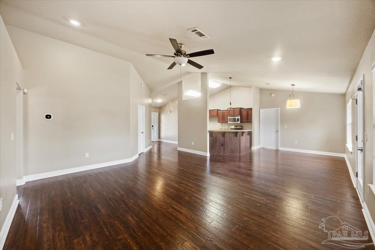 4015 Berry Circle Pace, FL 32571 - Photo 7 of 48 an empty room with wooden floor a ceiling fan and kitchen view
