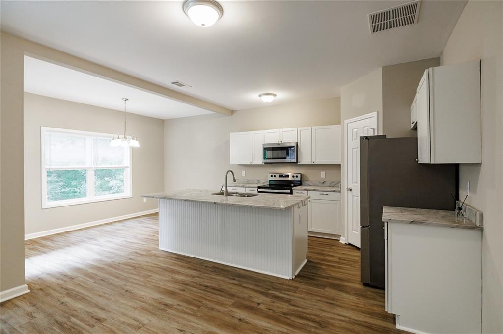 103 Three Rivers Court Hull, GA 30646 - Photo 11 of 40 a kitchen with stainless steel appliances a stove top oven a sink a refrigerator white cabinets and wooden floor