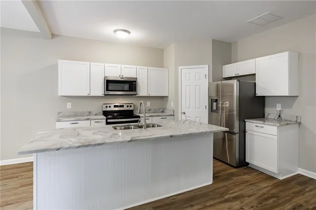 a kitchen with stainless steel appliances a stove a sink a refrigerator a microwave and cabinets