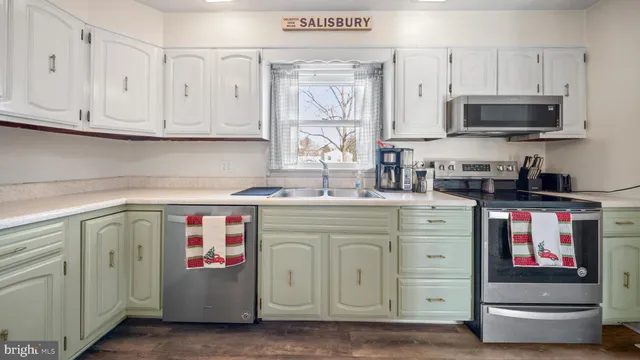 a utility room with stainless steel appliances granite countertop a stove a sink and a microwave