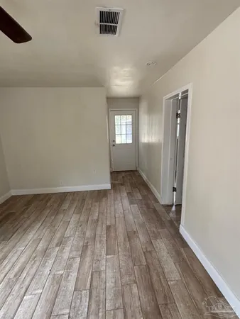 a view of empty room with wooden floor and fan