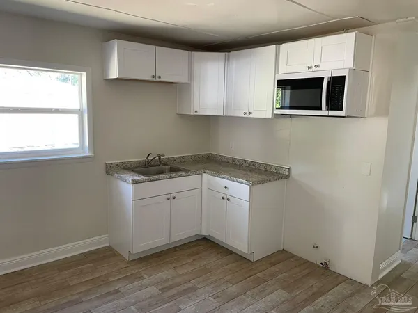 a kitchen with granite countertop white cabinets and white appliances