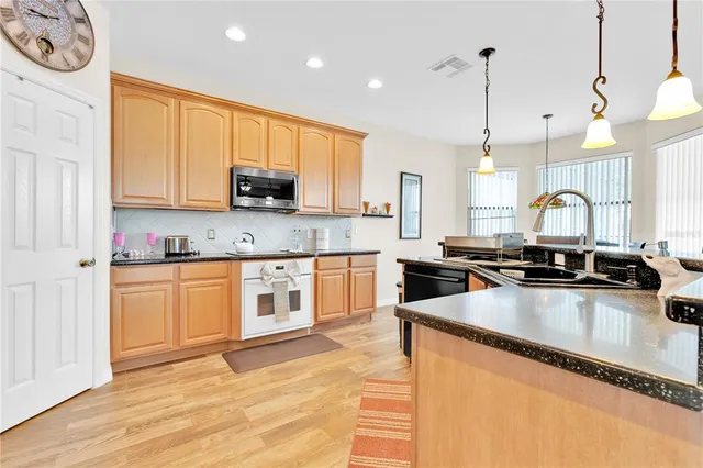 a kitchen with stainless steel appliances granite countertop a sink a stove and a refrigerator