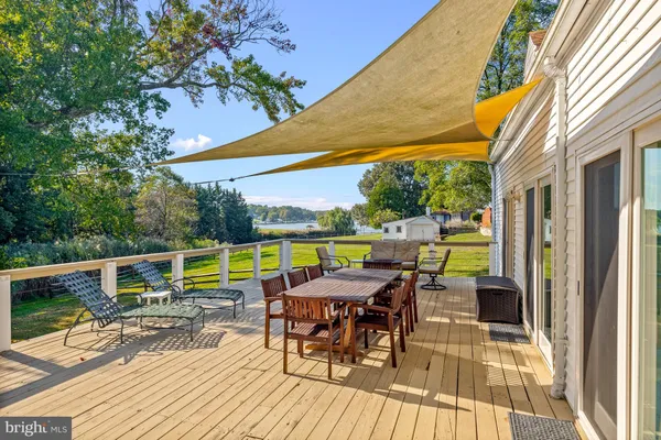 a view of deck with table and chairs under an umbrella next to a yard