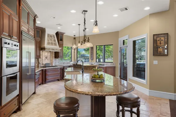 a kitchen with stainless steel appliances granite countertop a stove a refrigerator a kitchen island a dining table and chairs