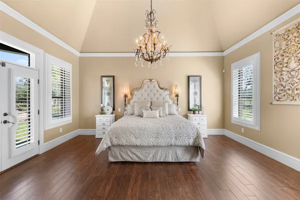 a spacious bedroom with a large bed chandelier and a window