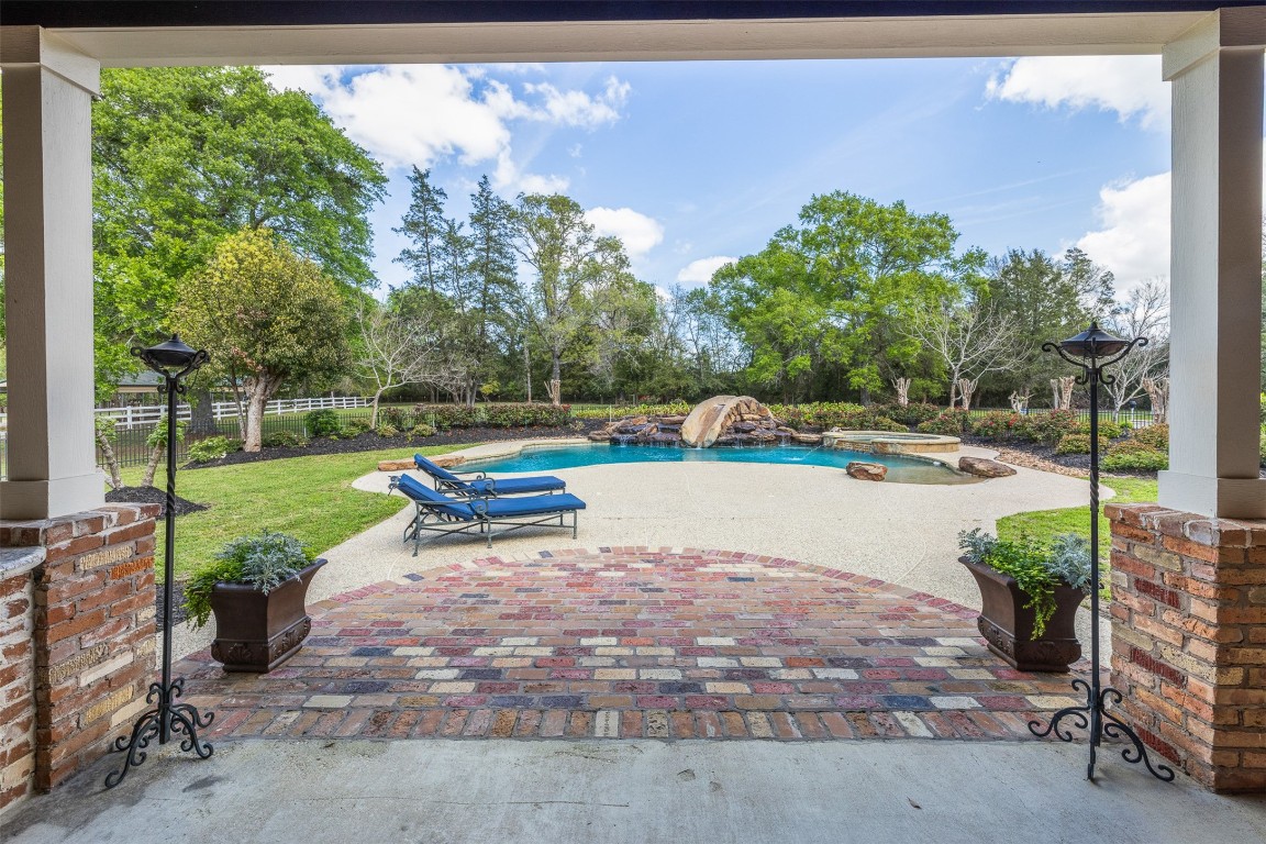29500 Skymac Ranch Road Hempstead, TX 77445 - Photo 39 of 50 A curved brick landing creates a graceful transition to the outdoor living spaces, where elegant poolside detailing, manicured landscaping, a dramatic rock waterfall, and a spa come together to form a true resort-style setting.