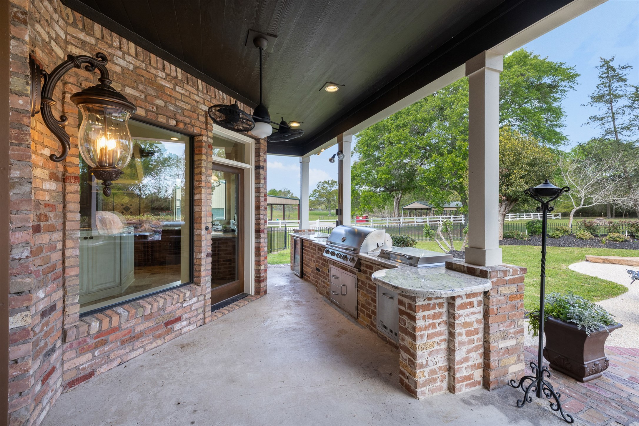 29500 Skymac Ranch Road Hempstead, TX 77445 - Photo 41 of 50
Designed for seamless indoor-outdoor living, the outdoor kitchen offers a built-in grill, refrigerator, and granite countertops, with direct access from the main kitchen and ceiling fans providing a comfortable environment.
