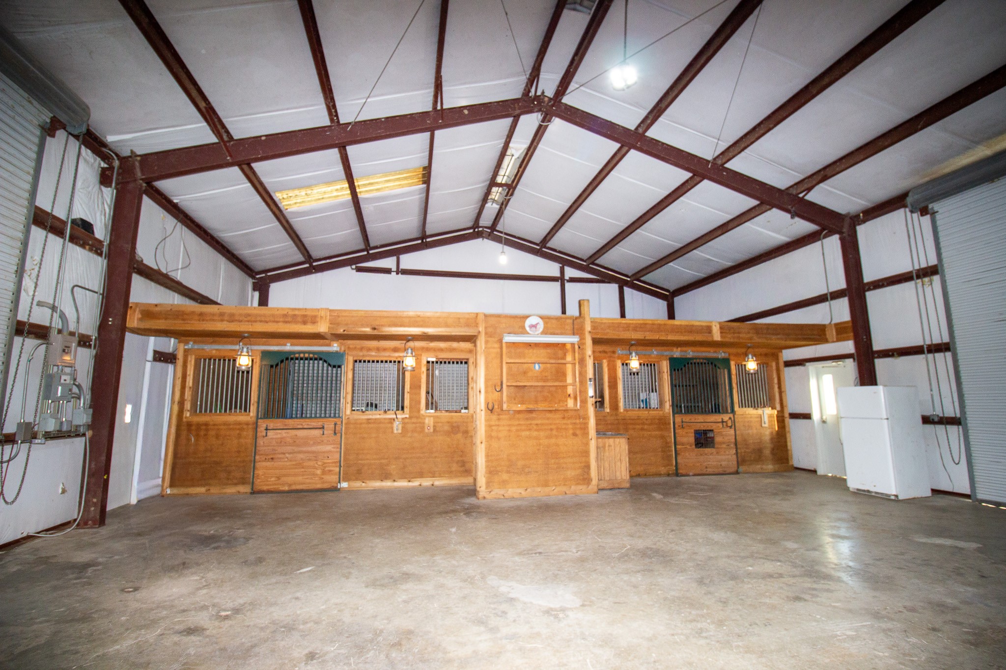 29500 Skymac Ranch Road Hempstead, TX 77445 - Photo 46 of 50 Designed with flexibility in mind, two stalls are accessible from within the shop, while a centrally positioned third stall opens to the exterior. Each features a private outdoor area, while 220 power and a dedicated 30-amp circuit, ideal for a welder or other high-demand equipment enhance the functionality of the space. A nearby half bath adds everyday convenience.