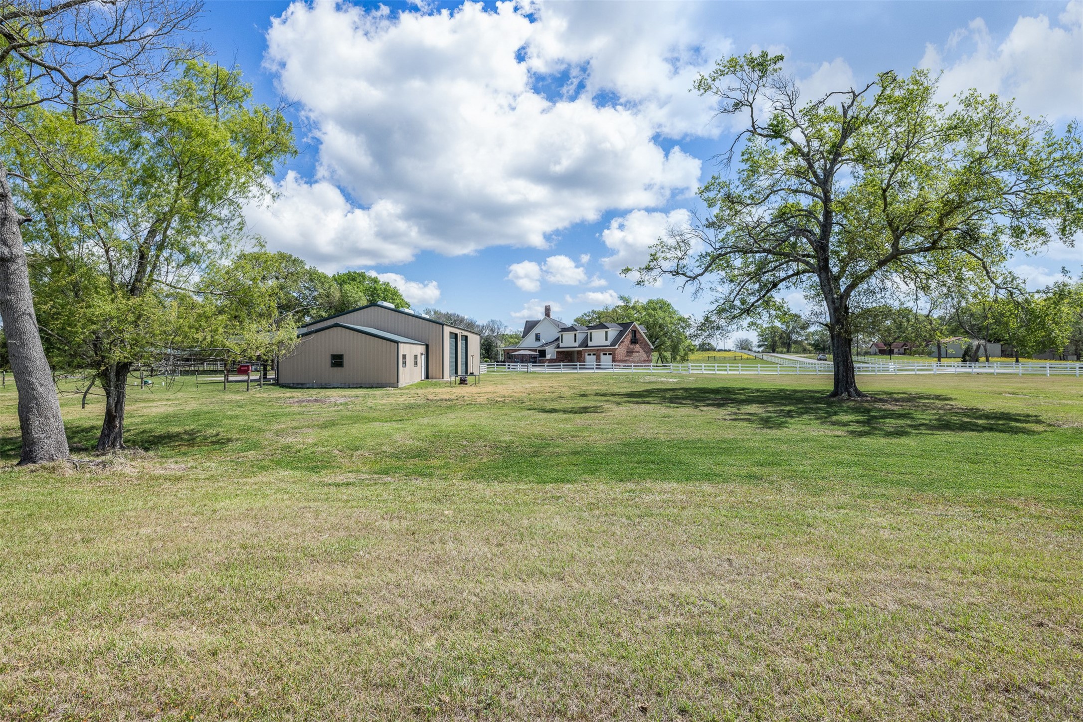 29500 Skymac Ranch Road Hempstead, TX 77445 - Photo 49 of 50 A sweeping pasture view highlights both the residence and shop, all set among stunning trees that enhance the property’s picturesque appeal.