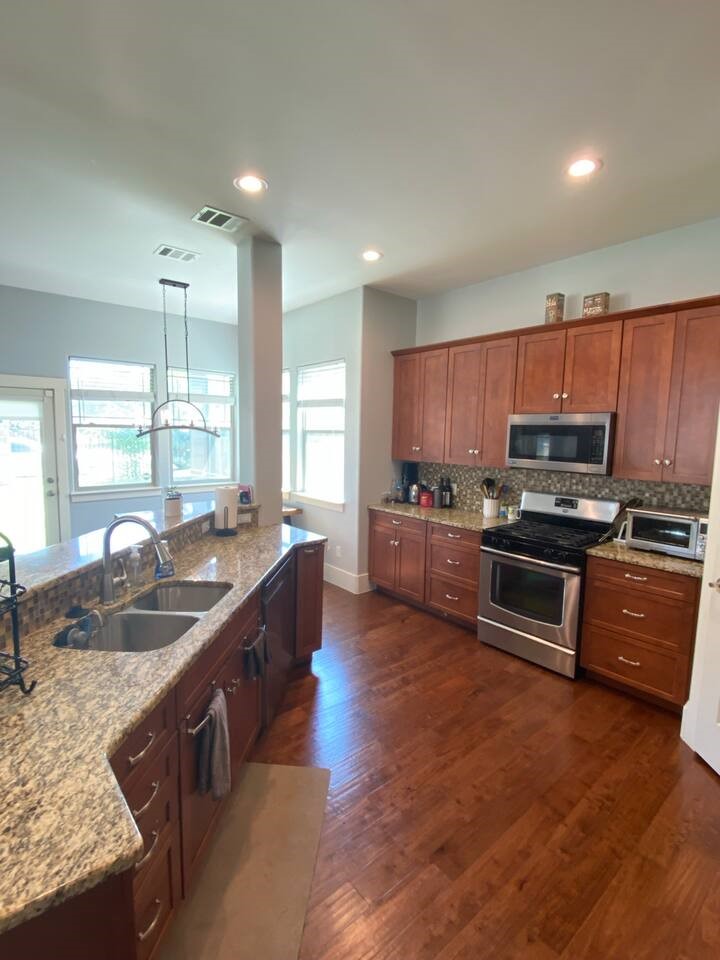 1007 Taulbee Lane, Unit A Austin, TX 78757 - Photo 6 of 17 a kitchen with stainless steel appliances granite countertop a stove a sink and a refrigerator