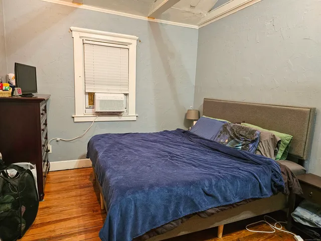 a bedroom with a bed and wooden floor