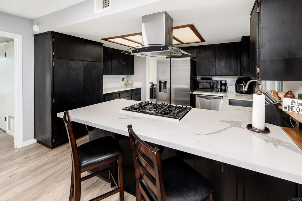 435 West Hawthorne Street Fallbrook, CA 92028 - Photo 12 of 42 a kitchen with stainless steel appliances a dining table chairs refrigerator and cabinets