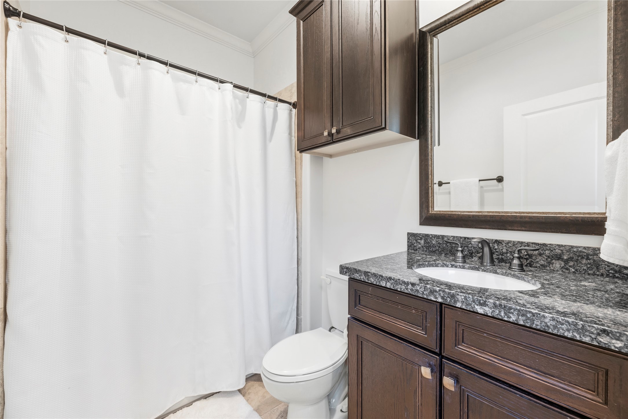 1537 Haddon Street Houston, TX 77006 - Photo 25 of 48 Second bathroom features a clean, modern design with dark wood cabinetry, a granite countertop, and a large mirror. It includes a bathtub with a shower, providing a fresh and functional space.