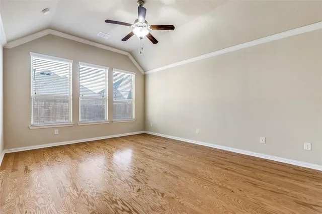 a view of an empty room with a window and wooden floor