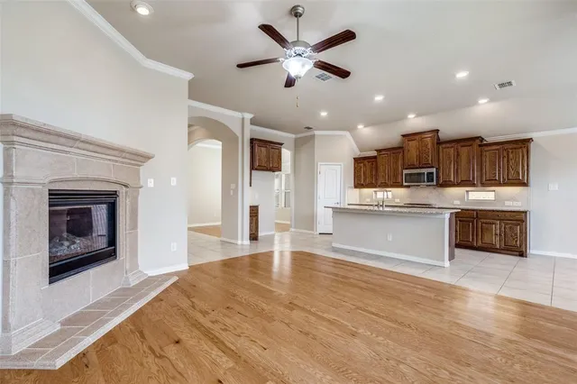 a large kitchen with kitchen island a stove a sink dishwasher and a fireplace with wooden floor