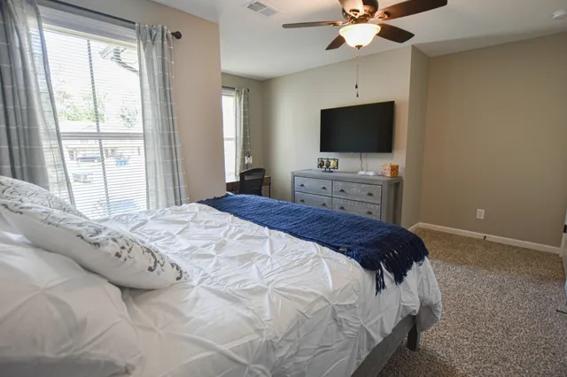 a bedroom with a bed tv and a window