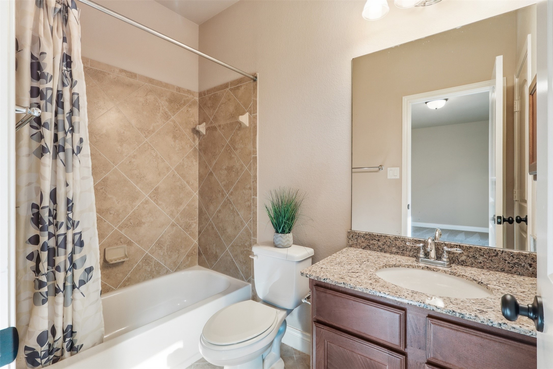 4130 Clover Ridge Lane Sugar Land, TX 77479 - Photo 25 of 48 This secondary primary bathrrom has a modern design with a granite countertop, a single sink and a wooden vanity. It includes a tub-shower combo with tile surround. The space is well-lit and connects to the secondary primary bedroom.