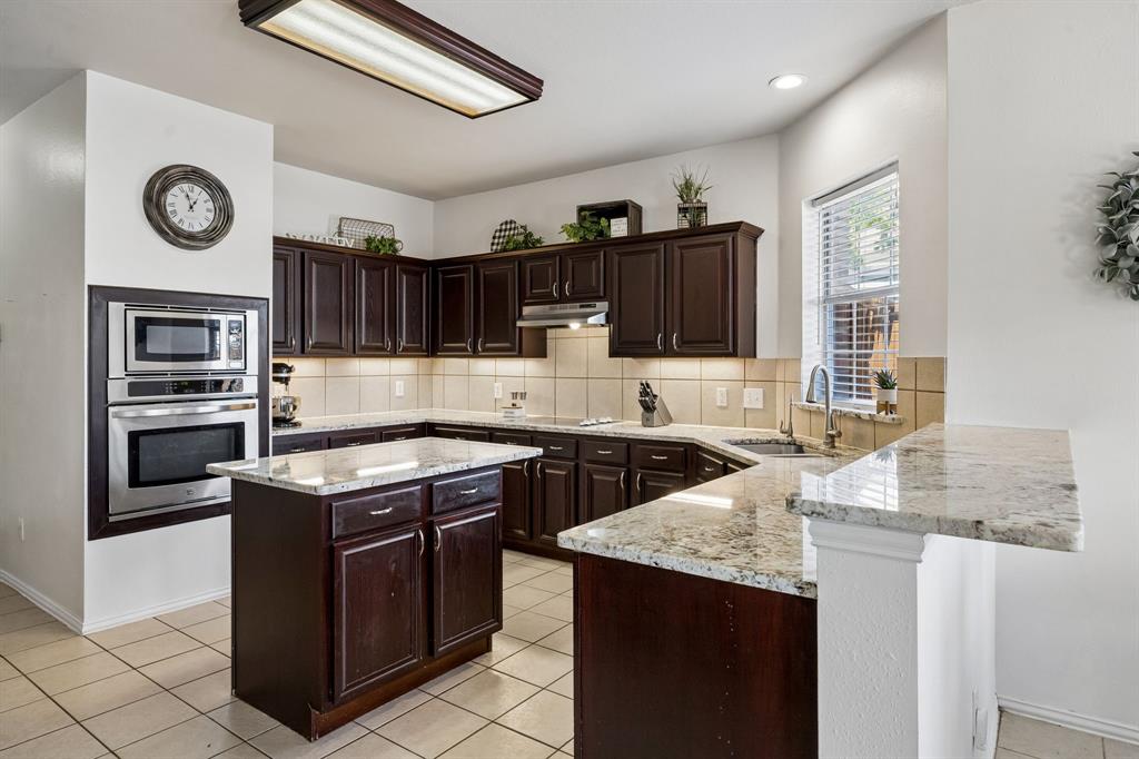 5315 Summit Knoll Trail Sachse, TX 75048 - Photo 4 of 40 a kitchen with stainless steel appliances granite countertop a stove a sink and a microwave
