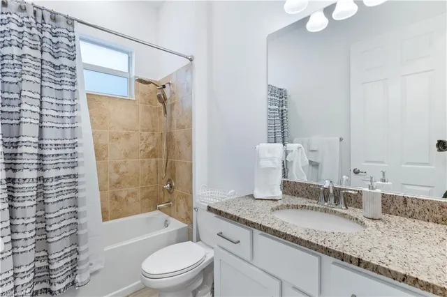 a bathroom with a granite countertop sink a toilet and shower