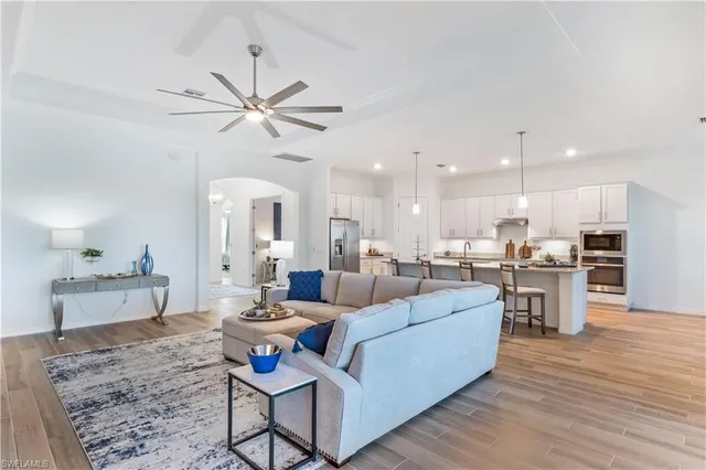 a living room with stainless steel appliances kitchen island granite countertop furniture wooden floor and a rug