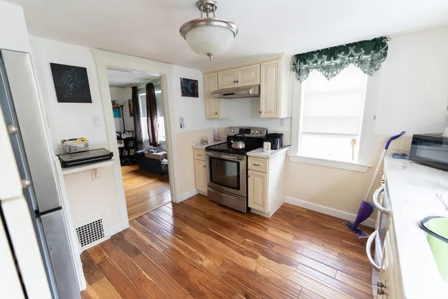 a kitchen with a refrigerator a stove a sink a window and a wooden floor