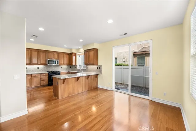 a large kitchen with kitchen island a sink wooden floor and stainless steel appliances
