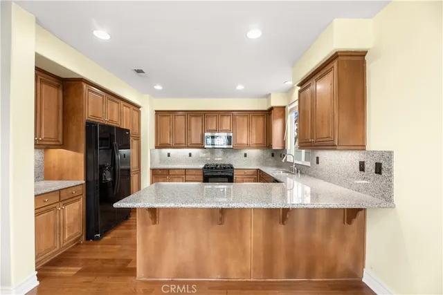 a large kitchen with kitchen island granite countertop a sink refrigerator and cabinets