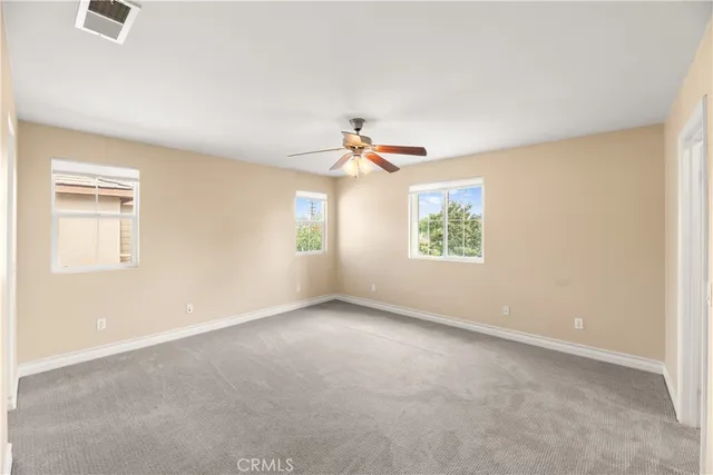 an empty room with windows and a ceiling fan
