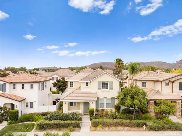 a view of a white house next to a yard with plants and large trees
