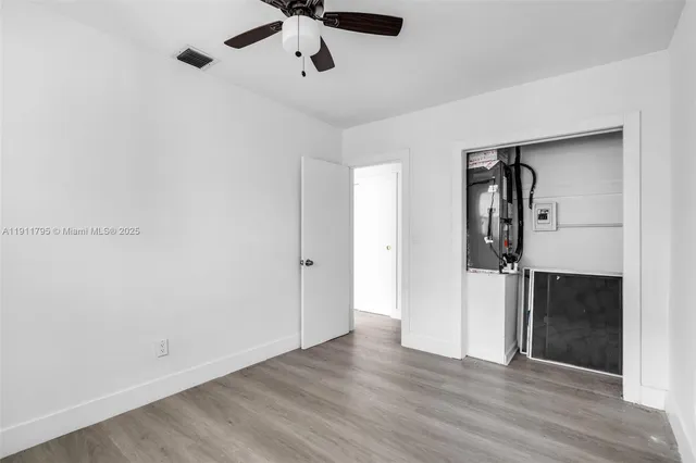 an empty room with wooden floor and a ceiling fan
