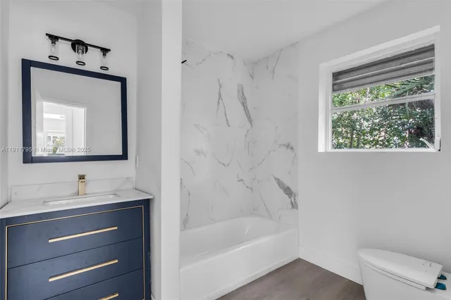 a bathroom with a tub sink toilet and mirror