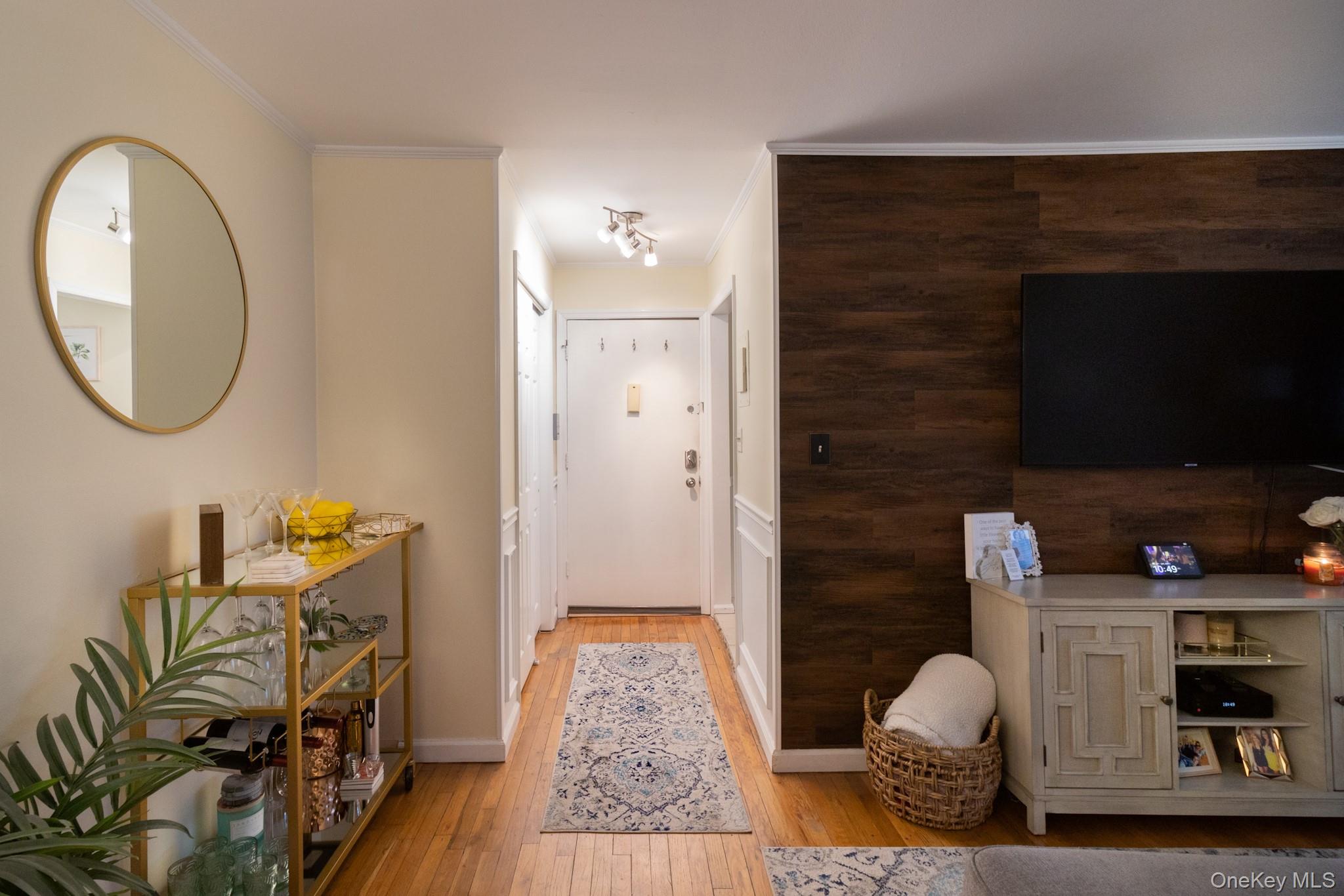 Entryway featuring light wood finished floors and ornamental molding