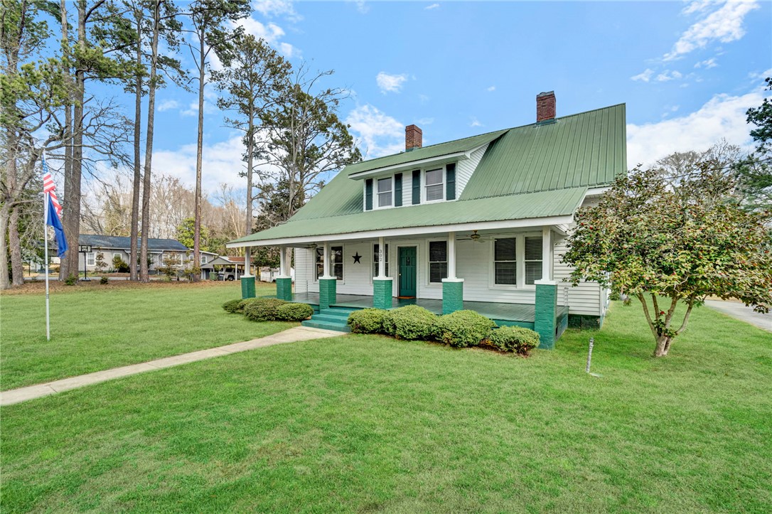 This charming home offers a welcoming facade with a classic porch and lush green lawn.