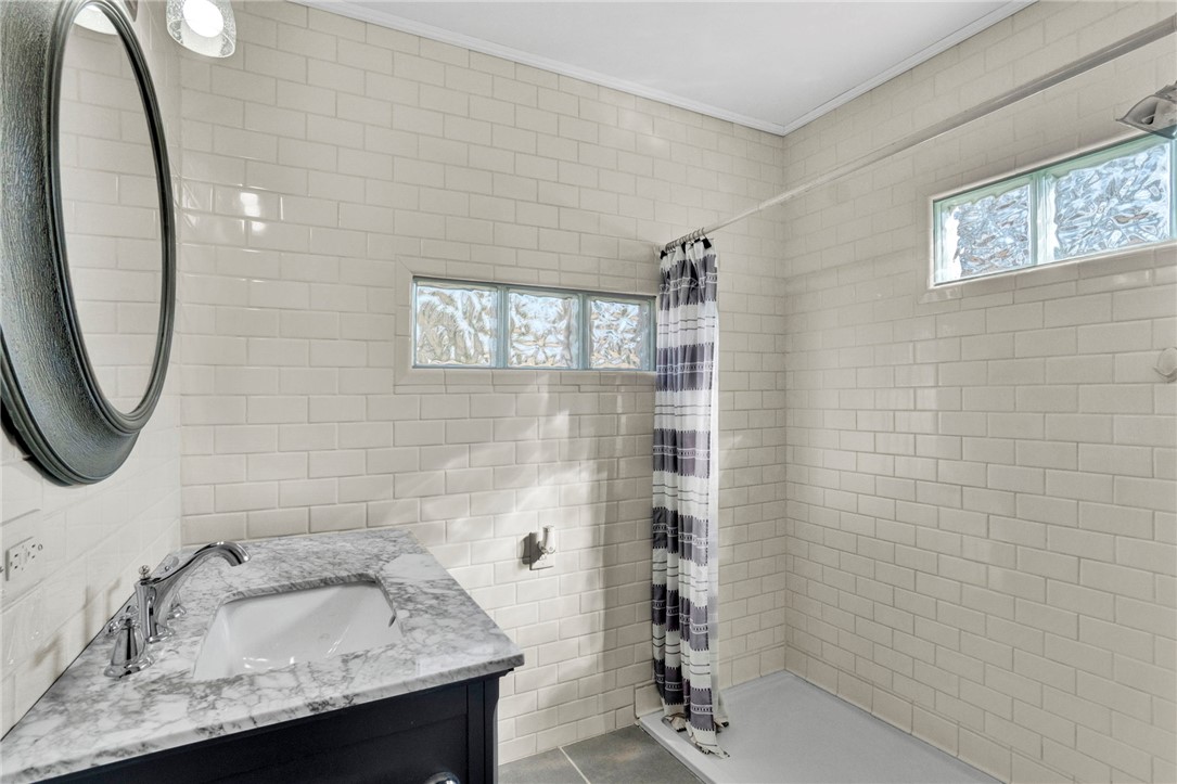 302 Gassaway Street Central, SC 29630 - Photo 13 of 34 This bright bathroom features subway tile, a marble-topped vanity, and a glass block window for natural light.